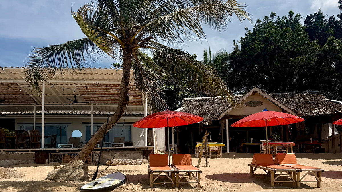 beach sun beds on beach in Koh Samui with red parasols and palm tree